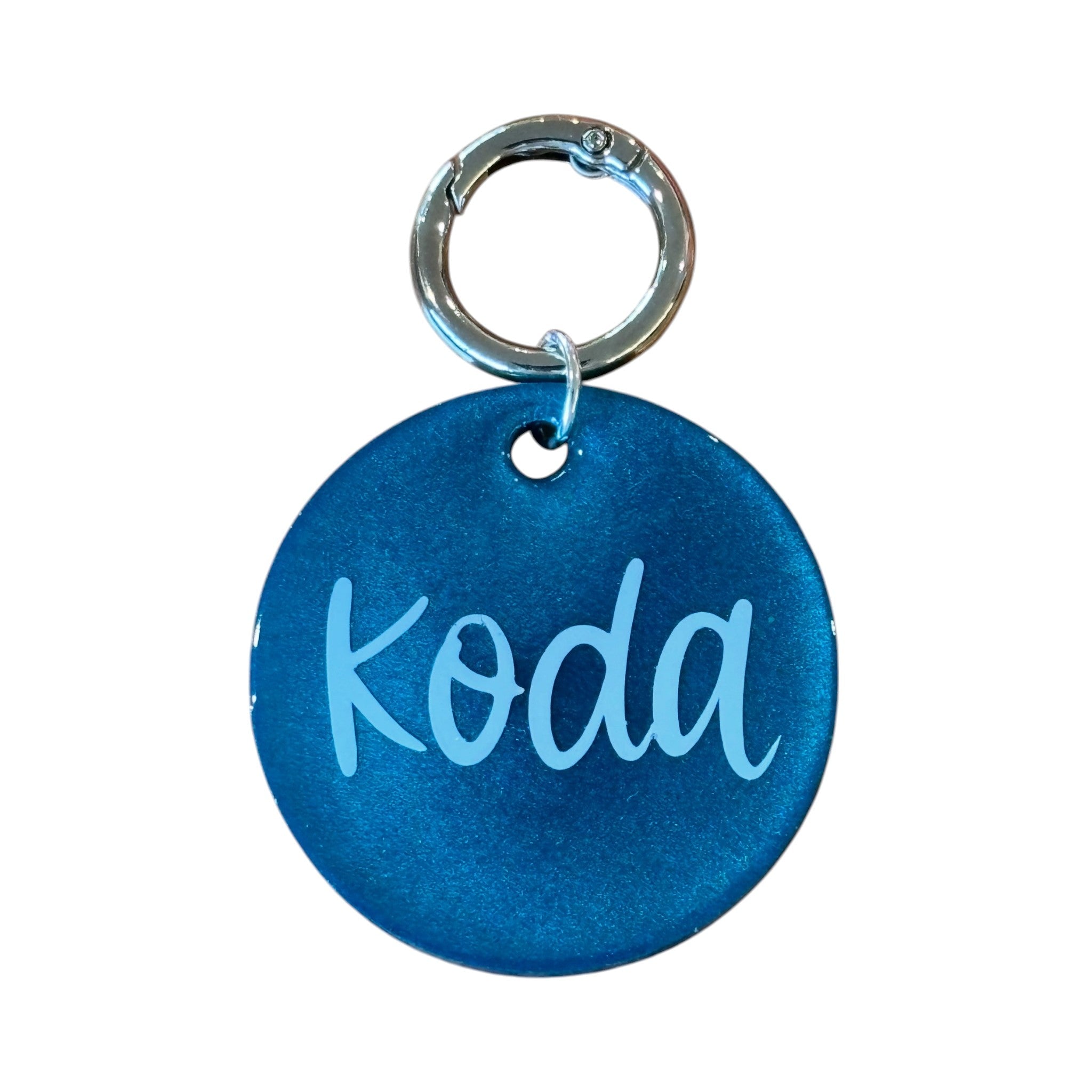 Blue round personalized dog tag with silver ring, engraved with the name Koda