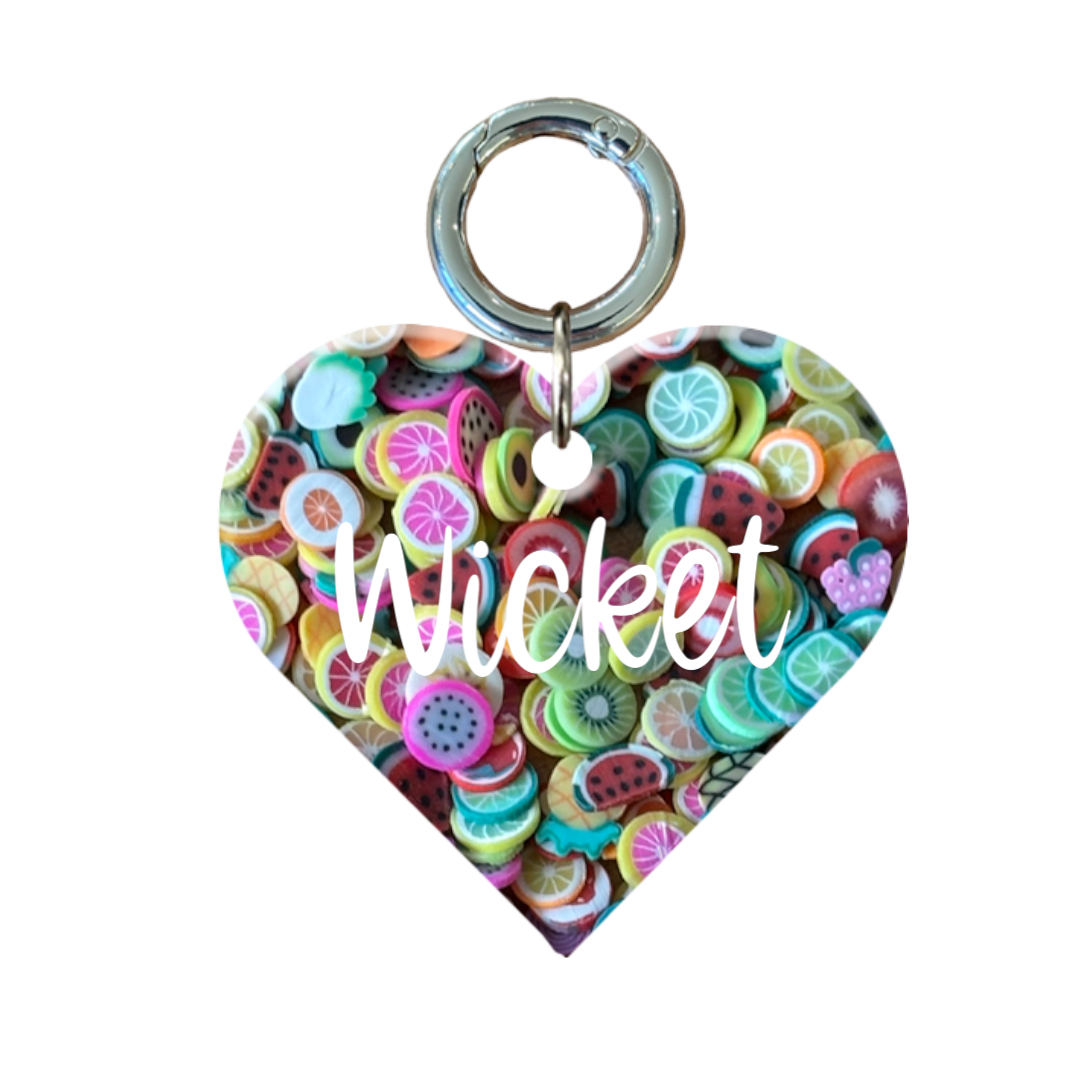 Heart-shaped dog tag with colorful fruit pattern and the name 'Wicket' on the front