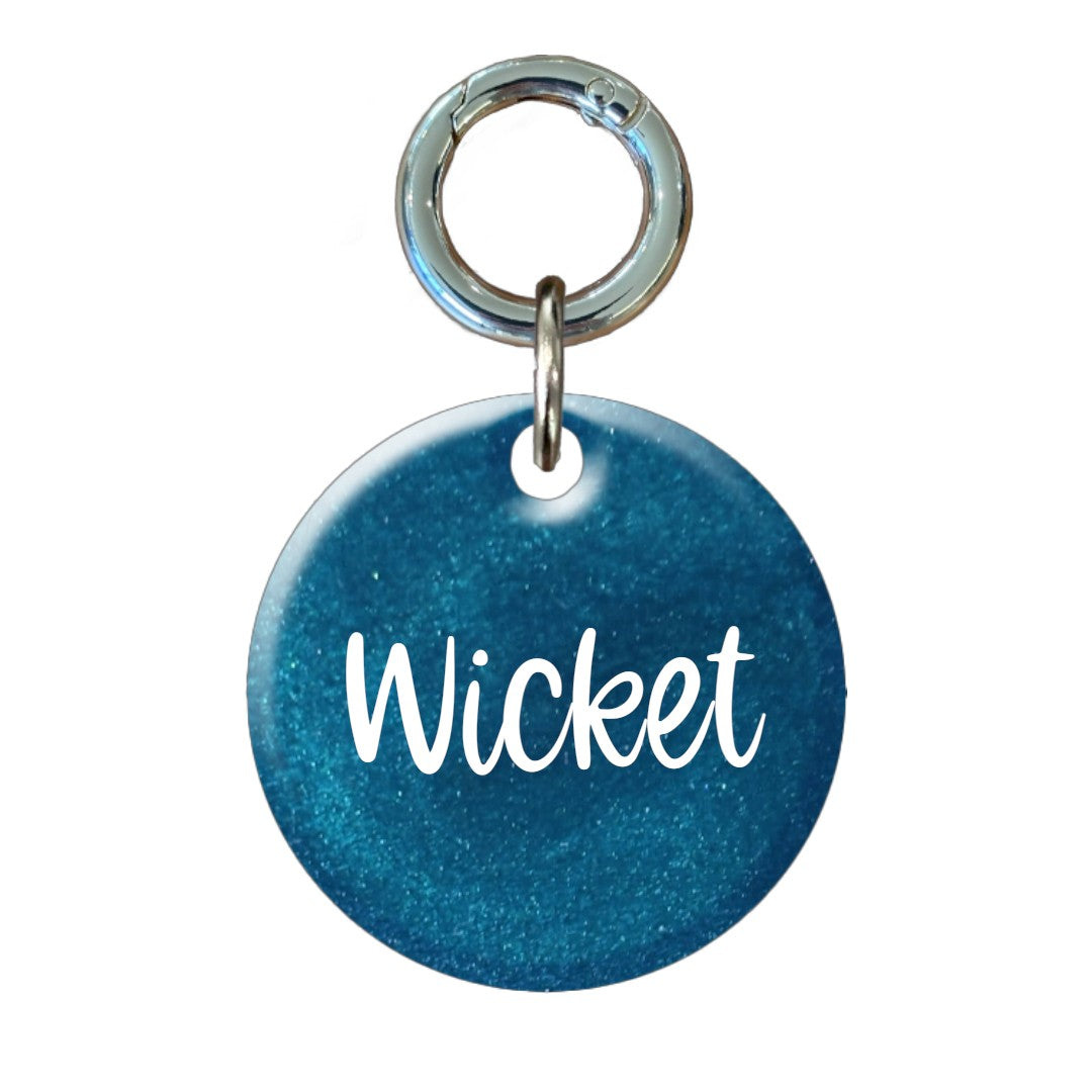 Blue glitter round dog tag with 'Wicket' name engraving and silver keyring attachment.