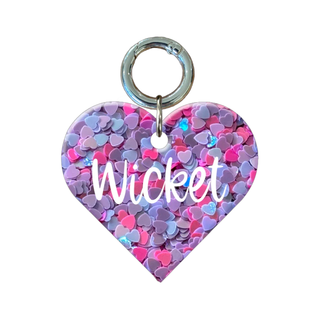 Personalised heart-shaped dog tag with pink and purple heart pattern and name Wicket.