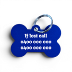 A bone-shaped blue pet ID tag with a silver metal key ring, featuring white printed emergency contact text on a white background.