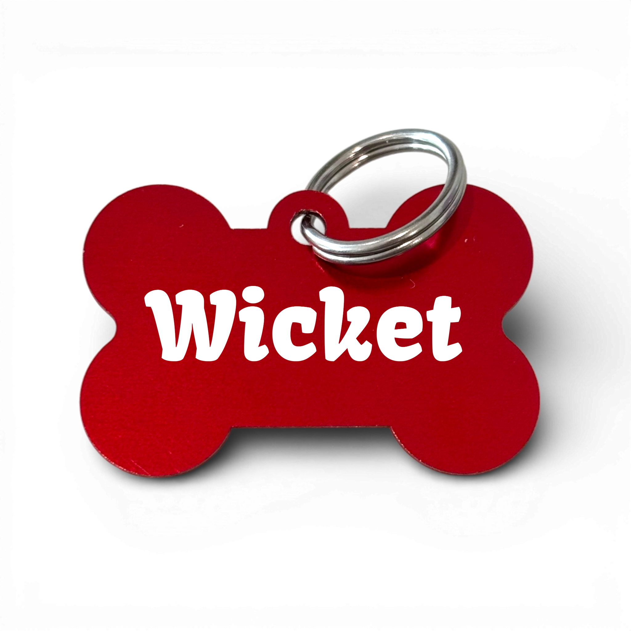 Red bone-shaped aluminium dog tag with 'Wicket' engraved, metal key ring attached